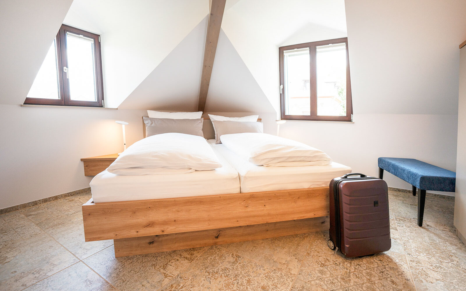 Helles Schlafzimmer mit Doppelbett und Koffer.
