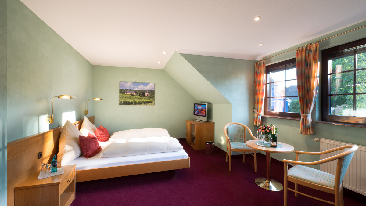 Helles Zimmer mit Doppelbett und Tisch.