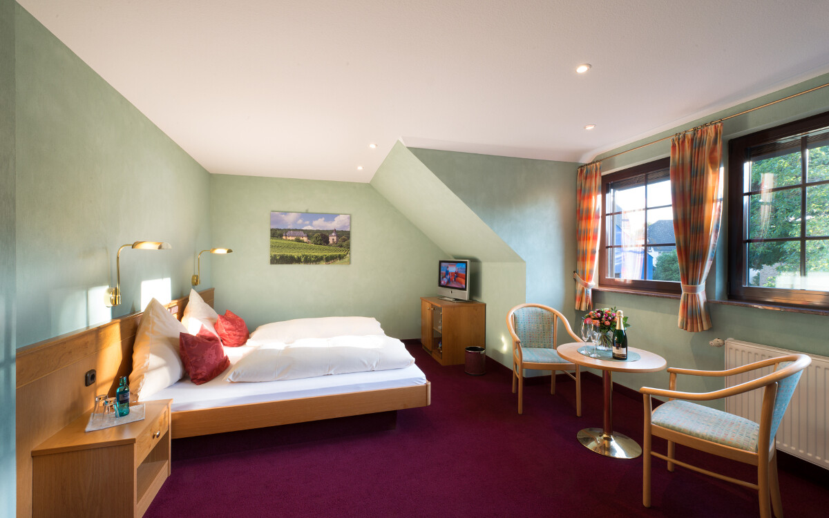 Helles Zimmer mit Doppelbett und Tisch.
