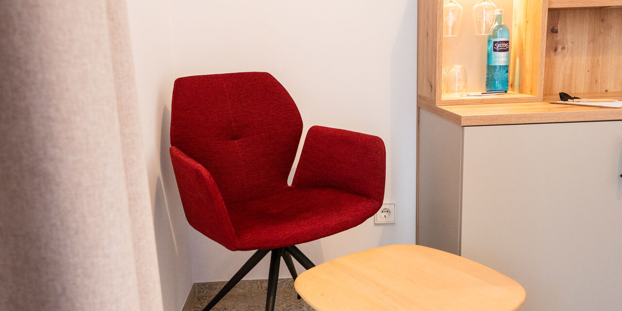 Roter Sessel und Holztisch.